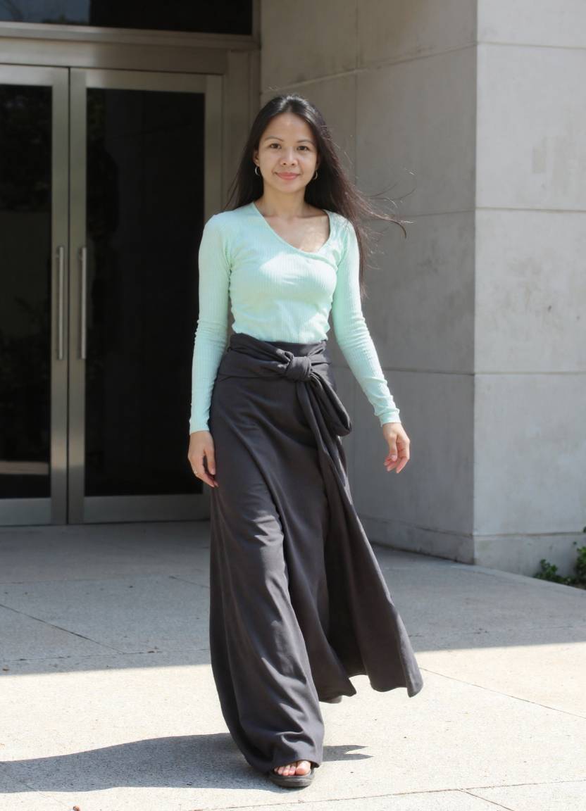 She approaches the glass entrance doors, walking forward — the building opens to receive her