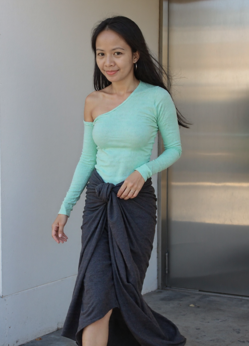 A still portrait near the corridor — she meets the viewer's gaze, mint off-shoulder top, architecture behind her